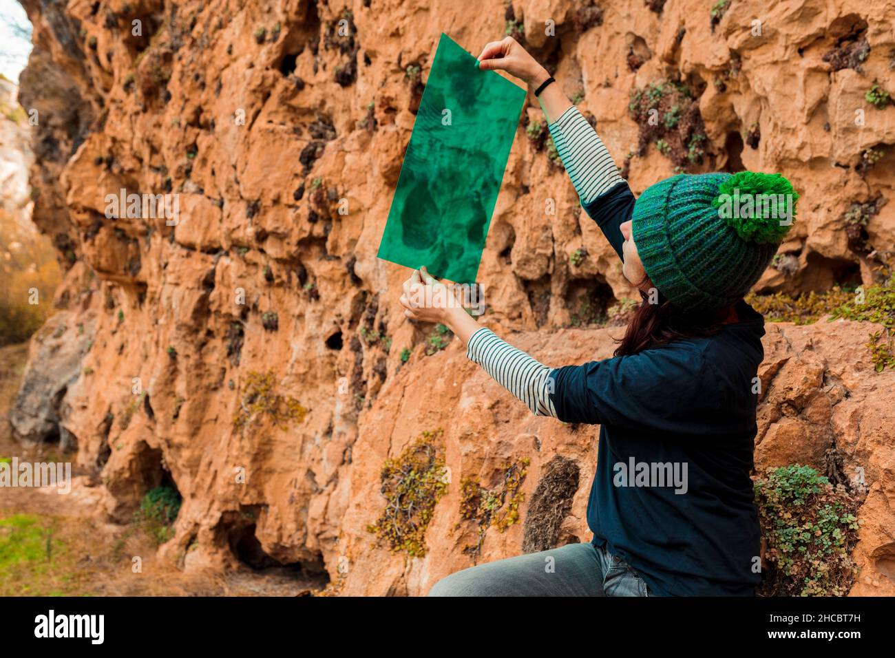 Woman looking through green color plastic sitting near mountain Stock Photo