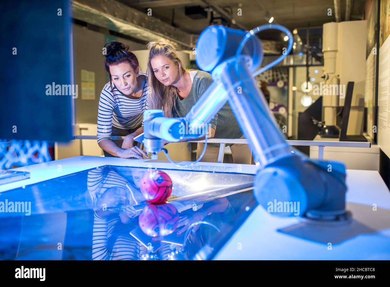 Tech developers looking at automated robotic arm at workshop Stock Photo