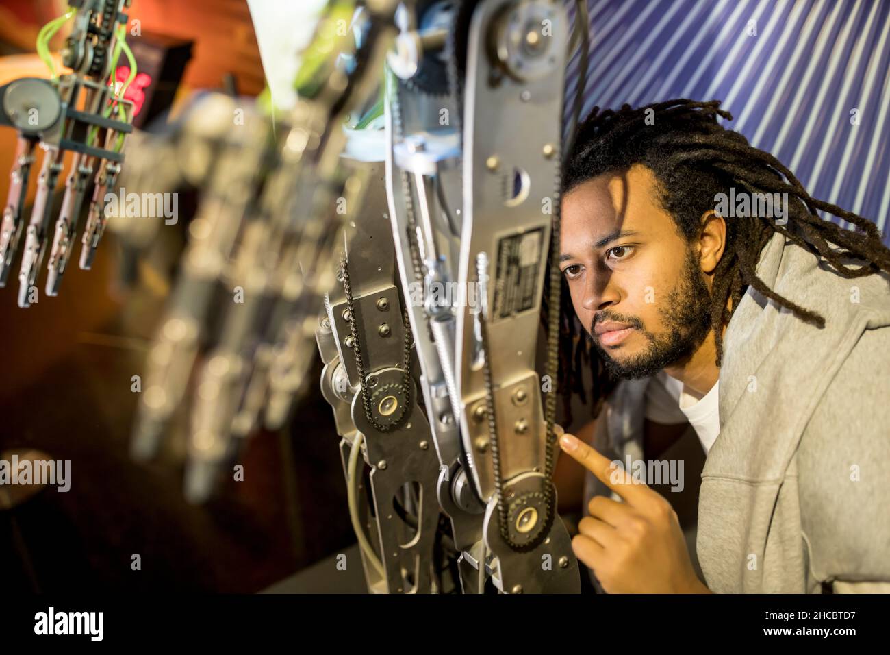 Young developer examining machine in human robot at workshop Stock Photo