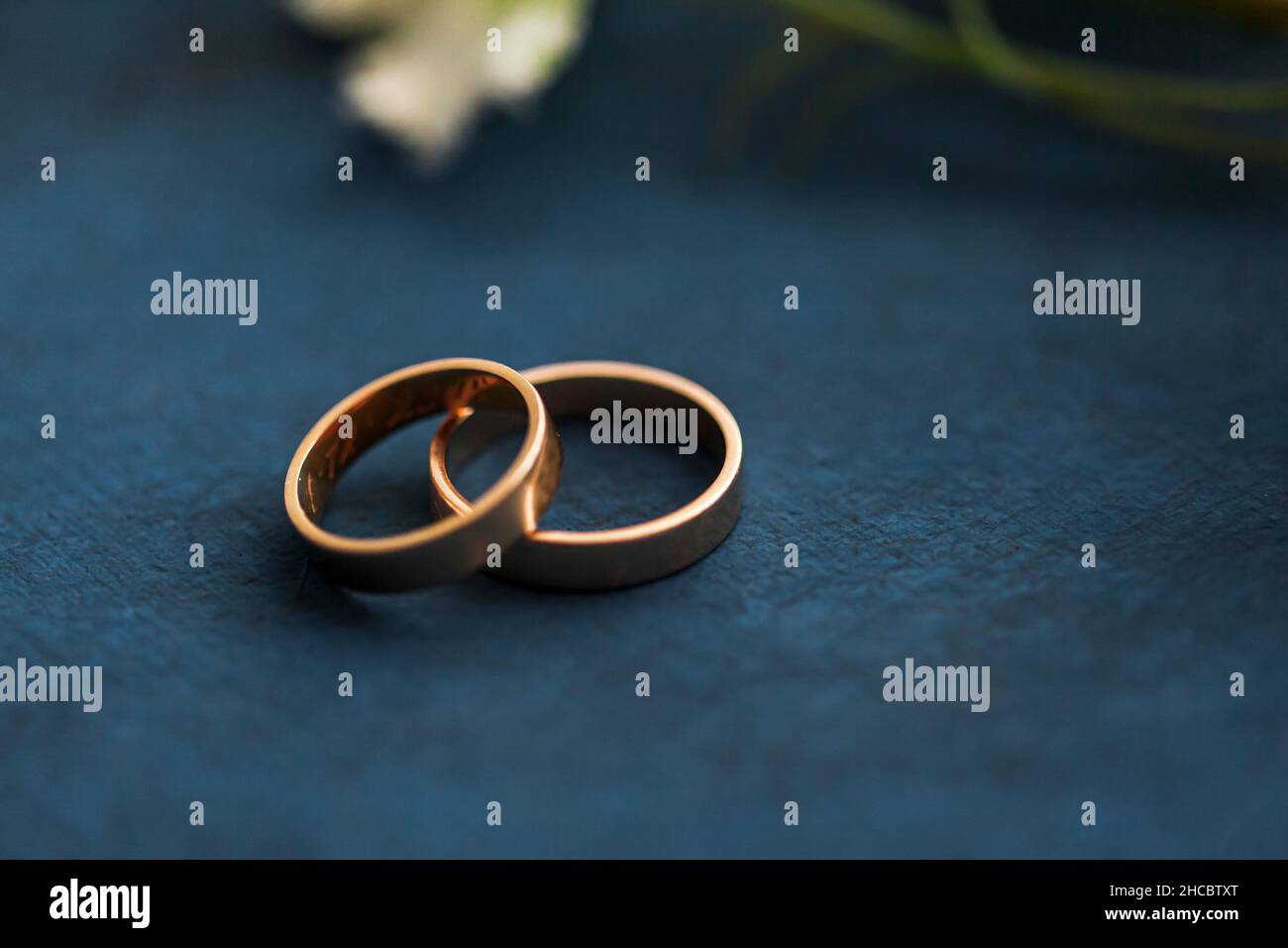 Studio shot of pair of golden wedding rings lying against brown background Stock Photo