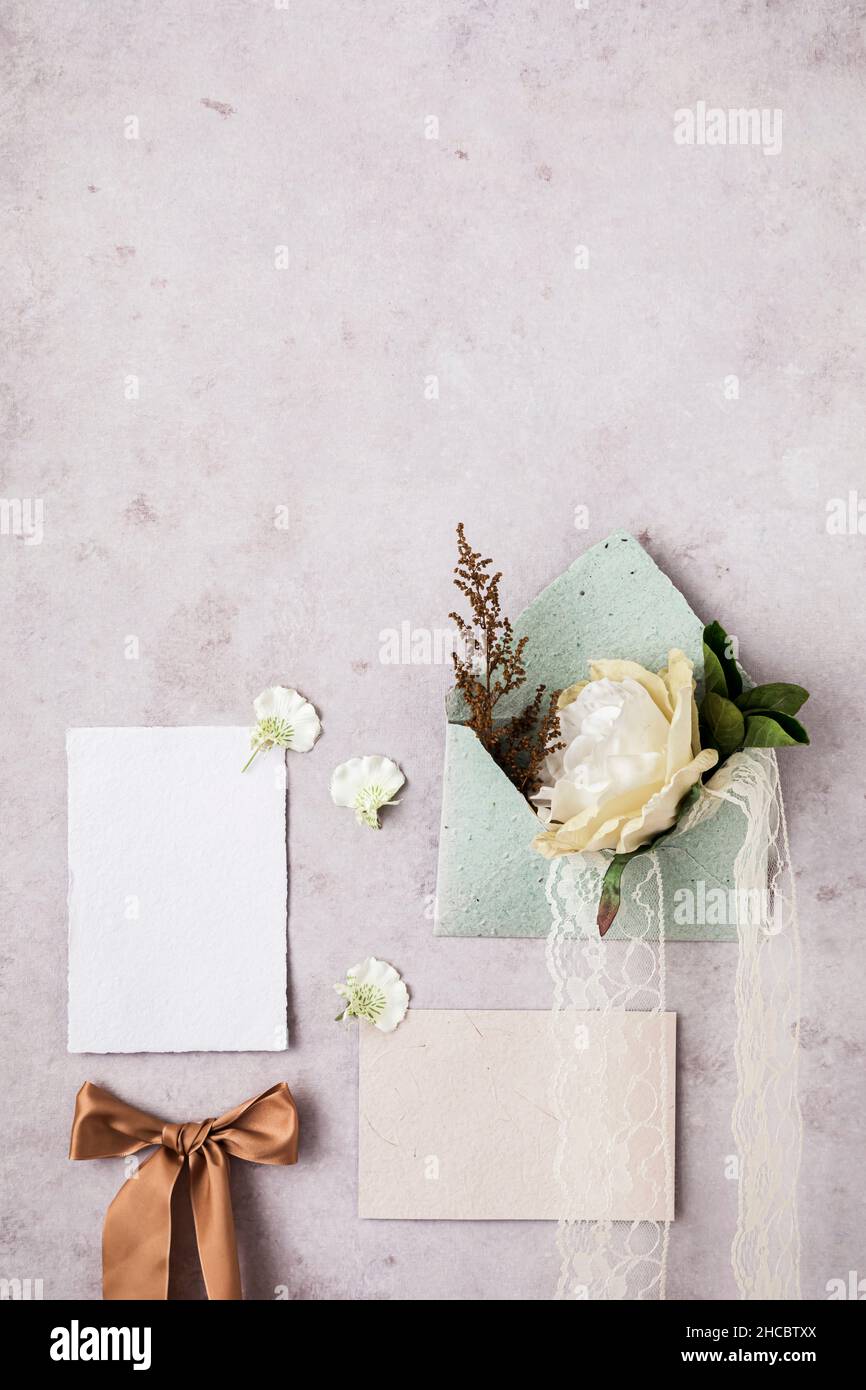 Studio shot of pair of wedding rings, invitation card and flower bouquet Stock Photo