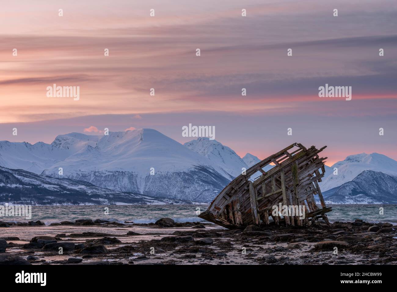 Shipwreck lying on shore of secluded Fjord at winter dawn Stock Photo