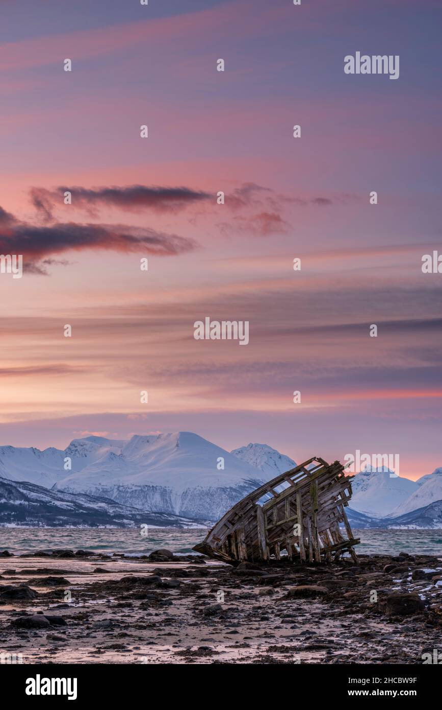 Shipwreck lying on shore of secluded Fjord at winter dawn Stock Photo