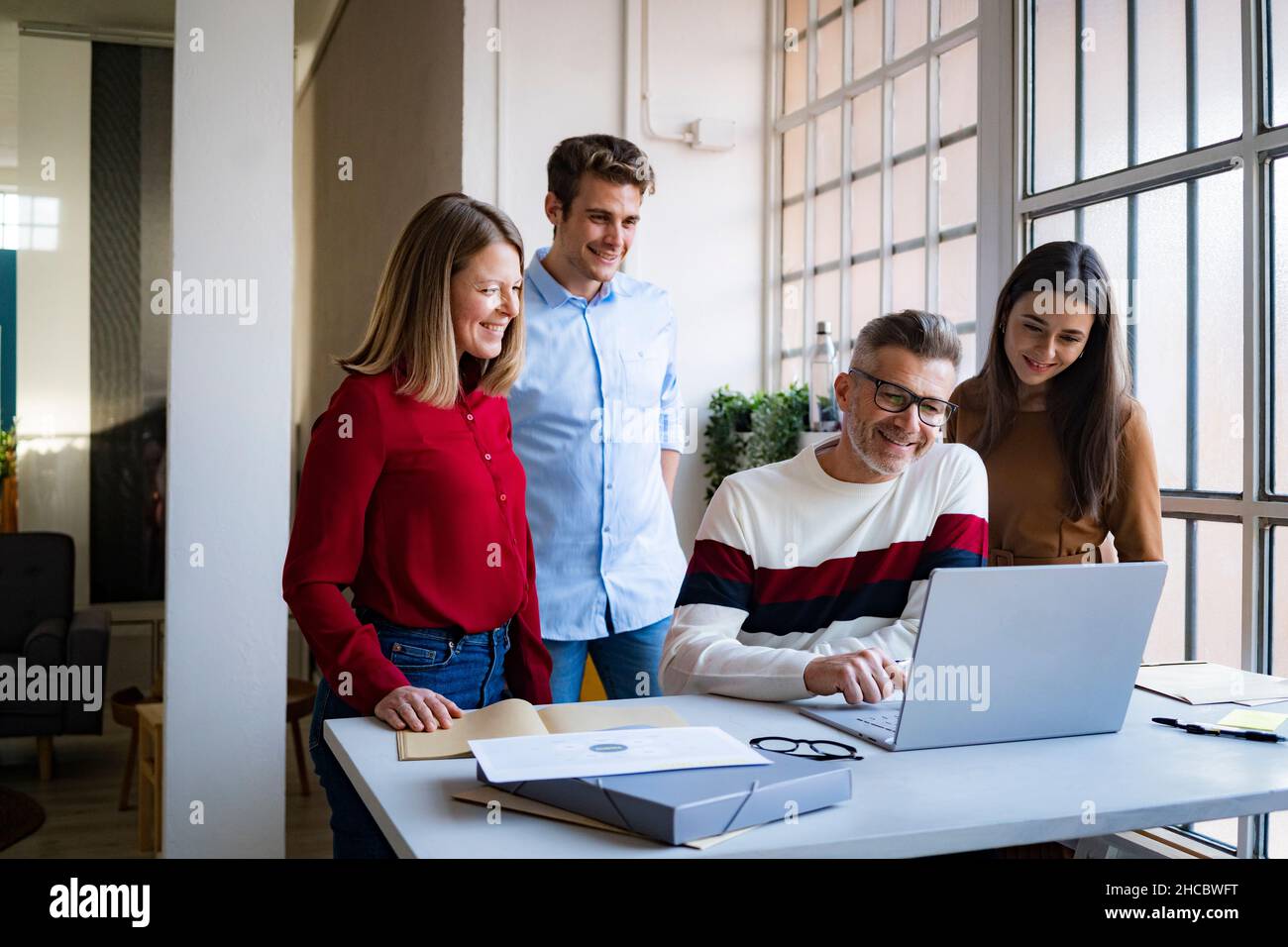 Businessman using laptop amidst colleagues in office Stock Photo