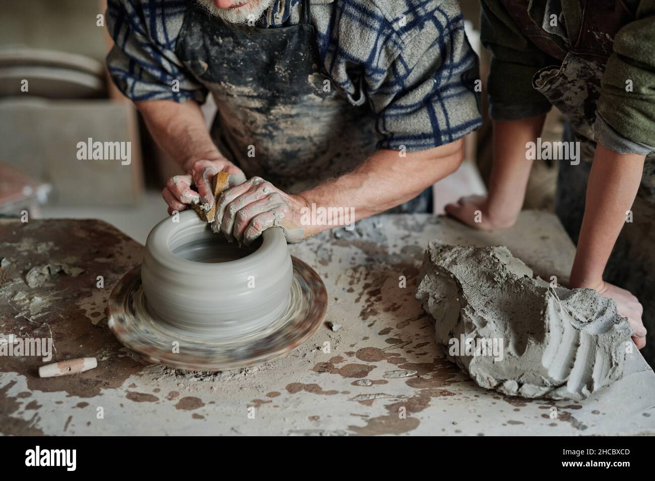 Close-up of pottery artist shaping clay on pottery wheel in workshop ...
