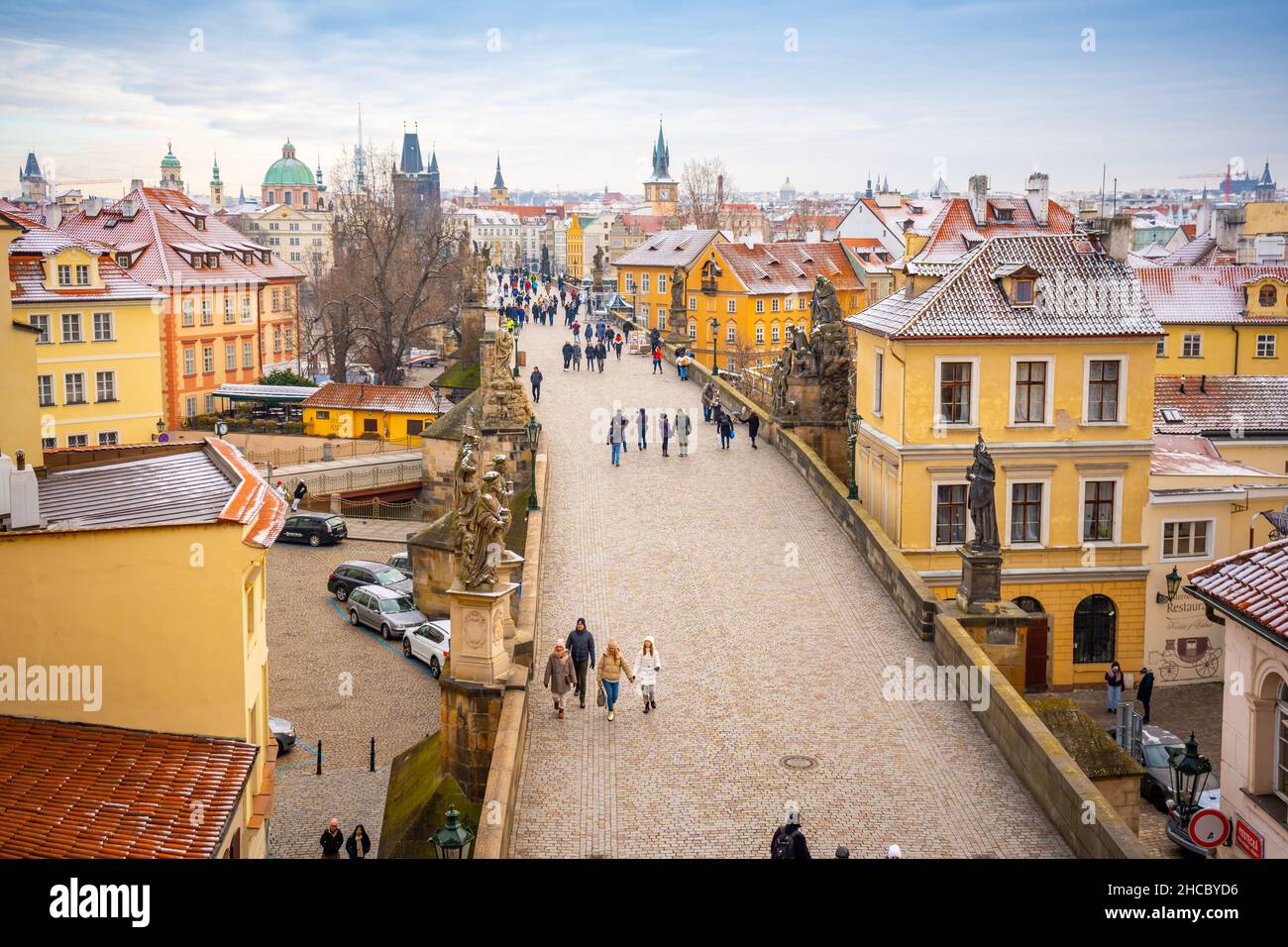 People are walking on Charles bridge, whose rooftops are covered by snow, Prague in the winter Stock Photo