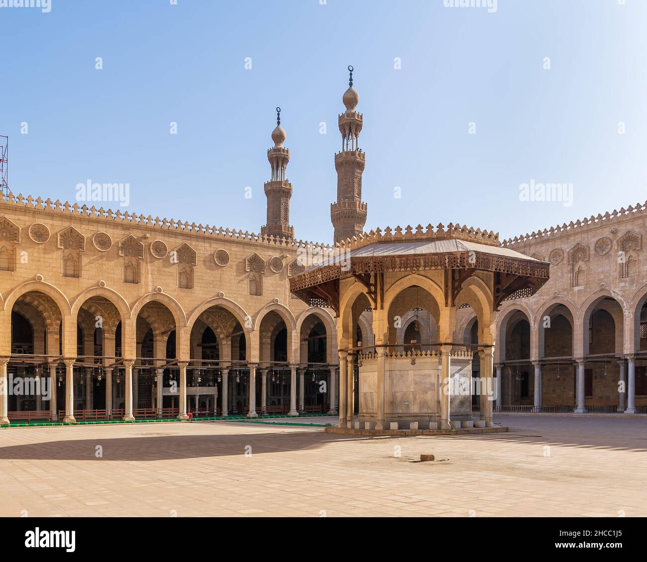 Ablution fountain mediating the courtyard of public historic mosque of Sultan al Muayyad, with background of arched corridors surrounding the courtyard, and minarets of the mosque, Cairo, Egypt Stock Photo