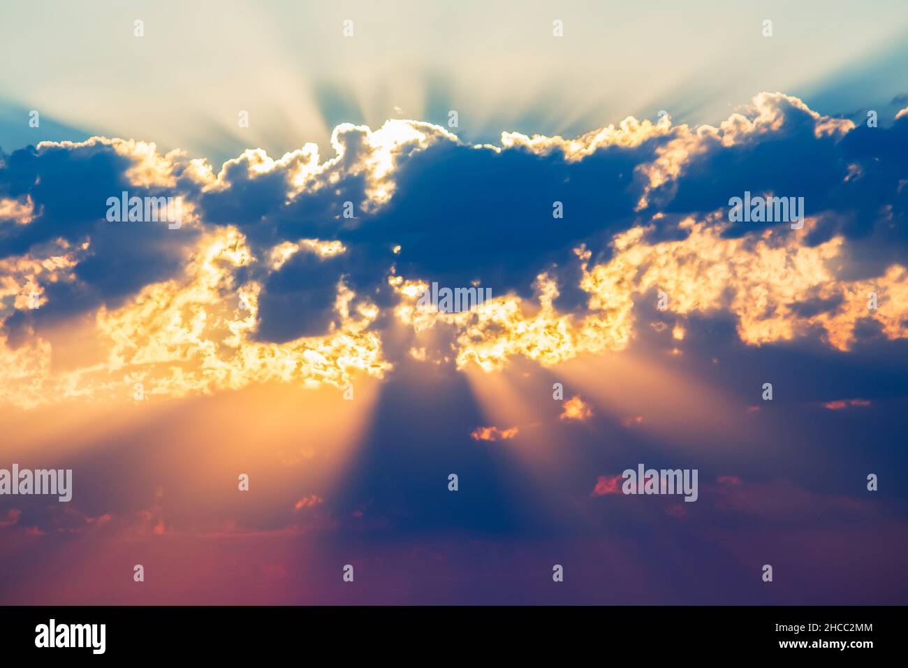 bright colored sunbeams behind the clouds Stock Photo