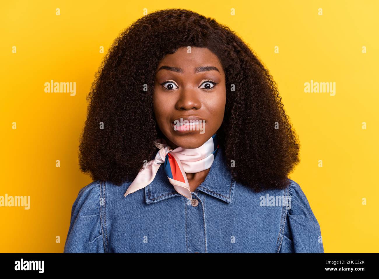 Portrait of questioned doubtful dark skin lady biting lip look camera isolated on yellow color background Stock Photo