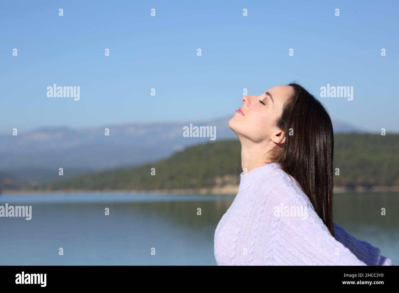 Side view portrait of a relaxed woman breathing fresh air in a mountain lake Stock Photo