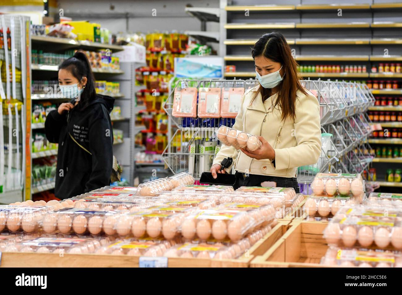 Dongxing, China's Guangxi Zhuang Autonomous Region. 27th Dec, 2021. A resident selects eggs at a supermarket in Dongxing City, south China's Guangxi Zhuang Autonomous Region, Dec. 27, 2021. Local government of Dongxing is making efforts to assure market supplies amid recent resurgence of COVID-19 cases in the city. Credit: Cao Yiming/Xinhua/Alamy Live News Stock Photo