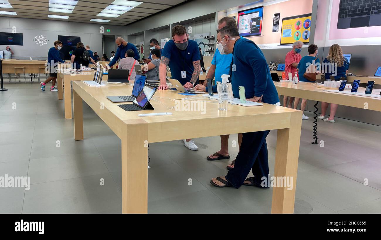Orlando, FL USA -September 20, 2021:  A salesperson and customers at an Apple store looking at a Apple  Macbook Air for sale. Stock Photo