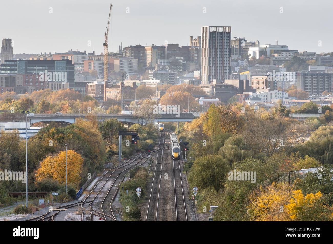 Great Western Railway intercity express passenger trains pass on the approach to Bristol Temple Meads station, with Bristol city centre behind. Stock Photo