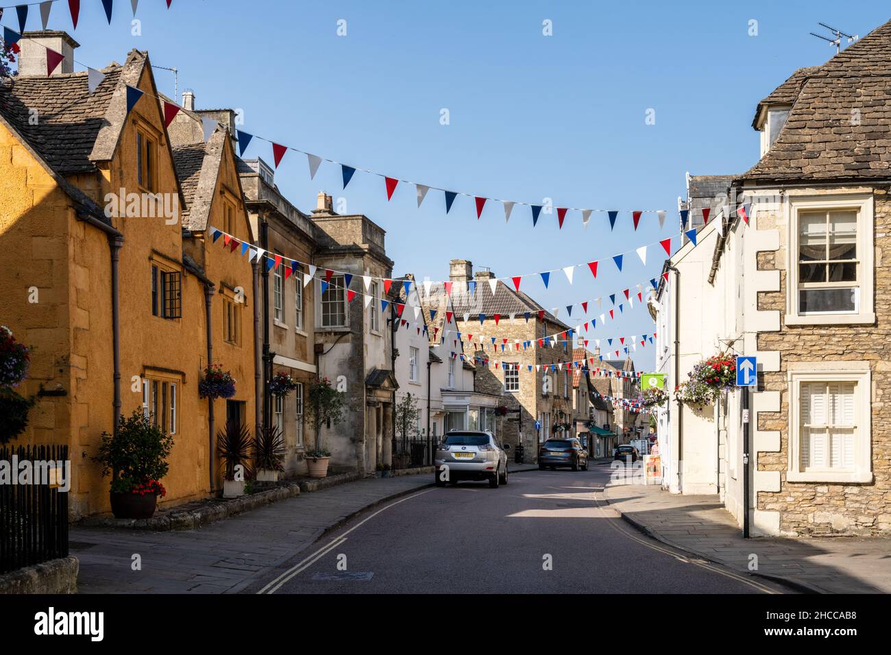 Shops and houses are decorated with bunting and flower baskets on the traditional High Street of