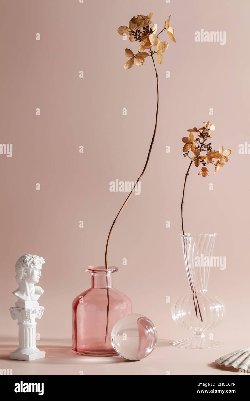 simplicity, naturalness, wabi sabi concept. dry flowers in vases on beige background. fashionable colored glass objects.  Stock Photo
