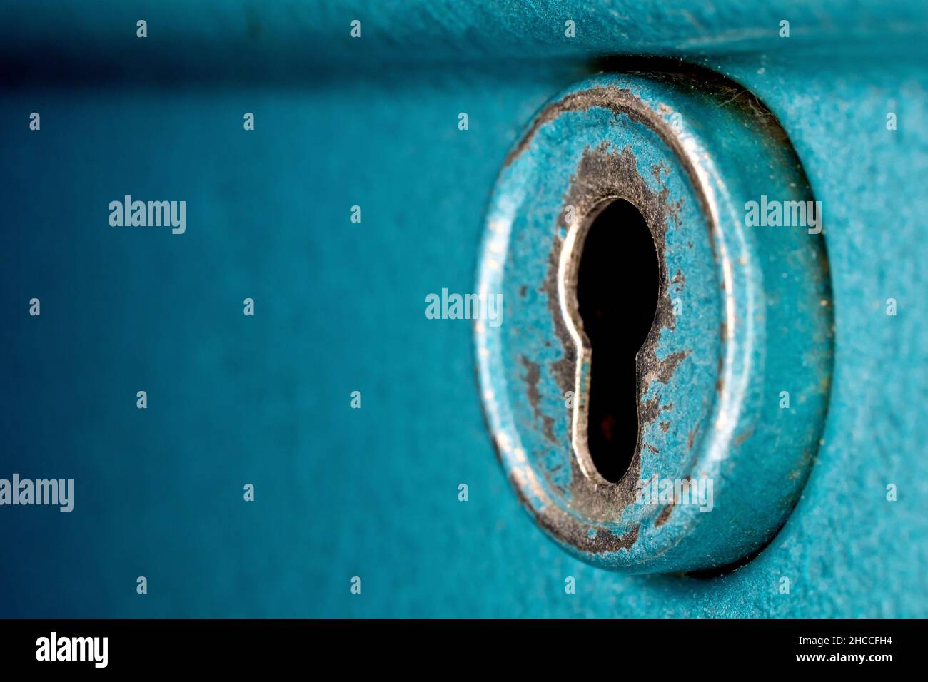 Close up still life of the round keyhole on an old blue metal cashbox. Stock Photo