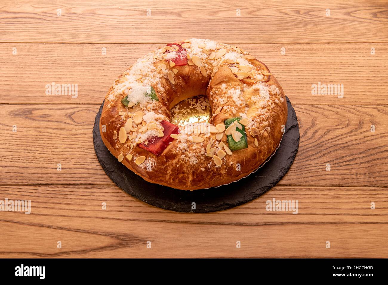 Roscón filled with cream with almonds, candied fruits, icing sugar and a golden tray Stock Photo
