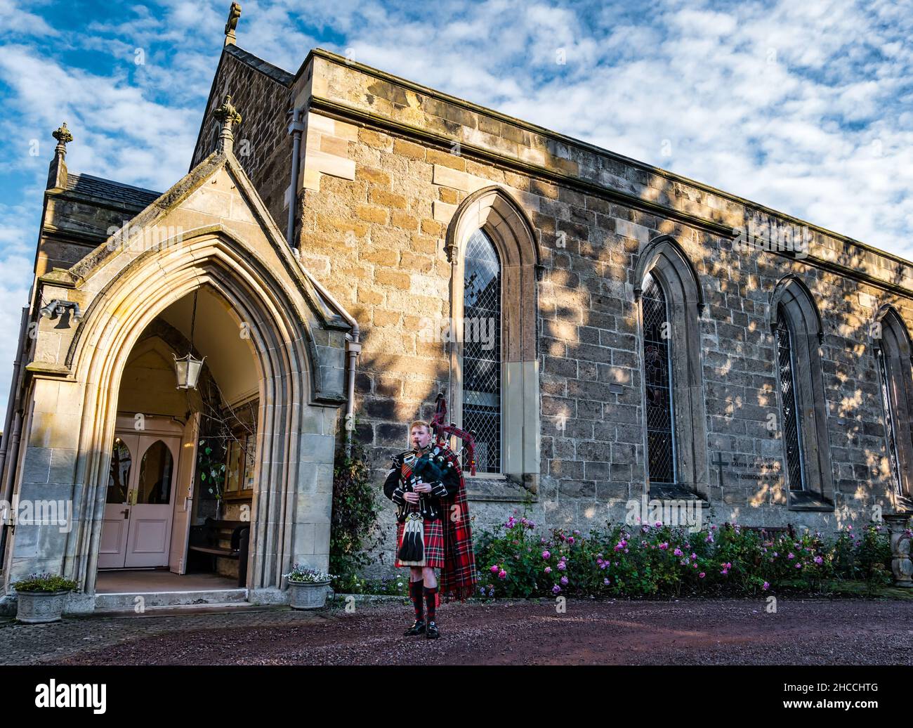 A piper from Scots Guards plays bagpipes outside Holy Trinity Church, Haddington, East Lothian, Scotland, UK Stock Photo