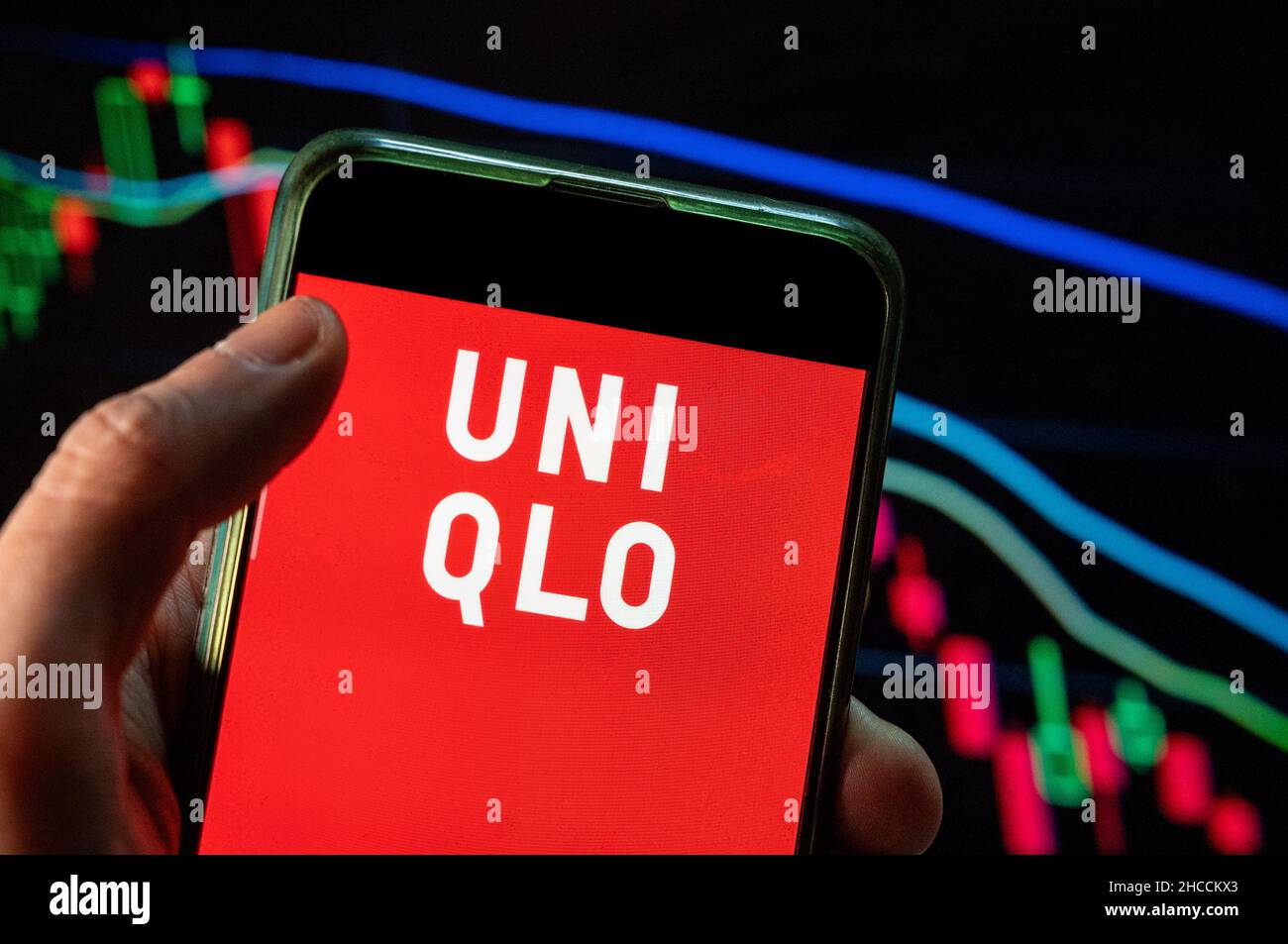 In this photo illustration the Japanese multinational clothing design  retail company Uniqlo logo seen displayed on a smartphone with an economic  stock exchange index graph in the background. (Photo by Budrul Chukrut /