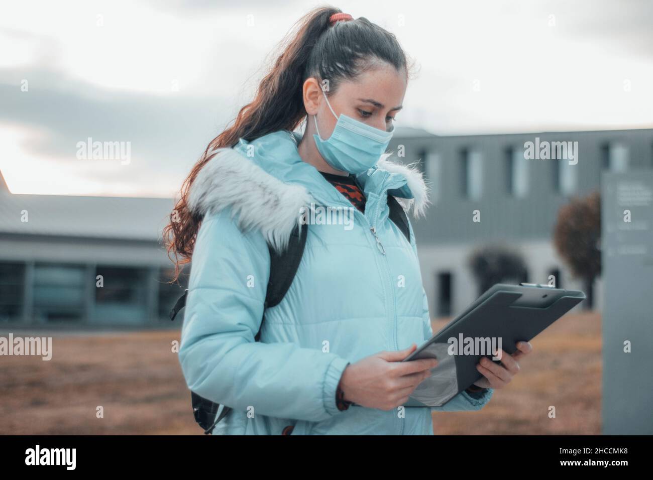 Young student girl with mask at school reviewing notes and her folder Stock Photo