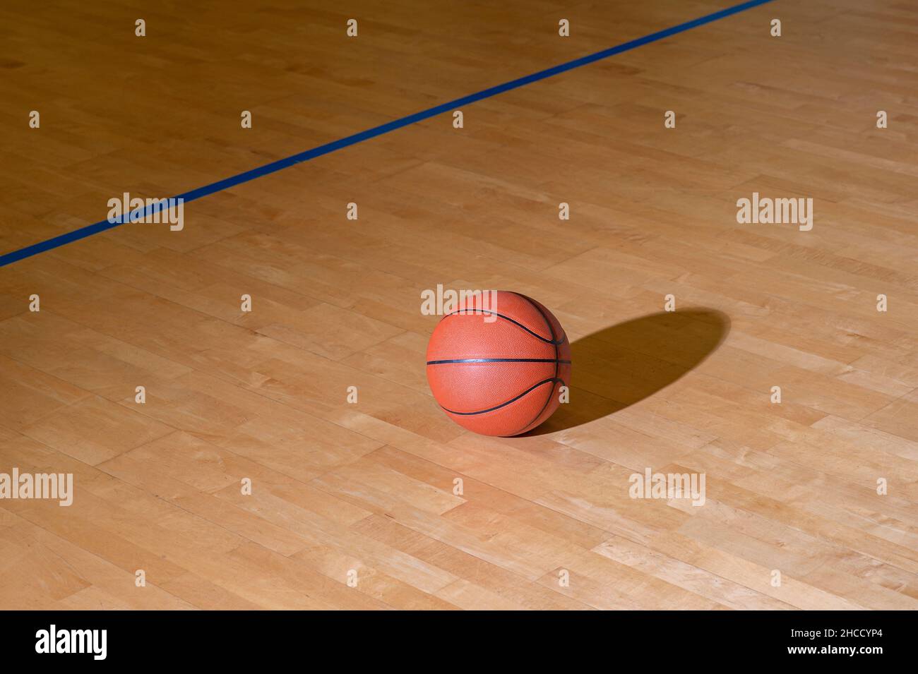 Basketball on hardwood court floor with natural lighting. Workout online concept. Horizontal sport theme poster, greeting cards, headers, website and Stock Photo