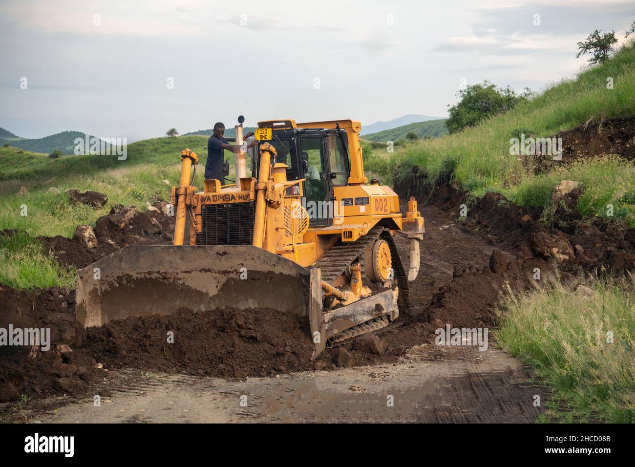 Tanzania, Arusha - January 2020: Excavator is Making Road in African Savannah. Group of African black men working for the construction of a road over Stock Photo