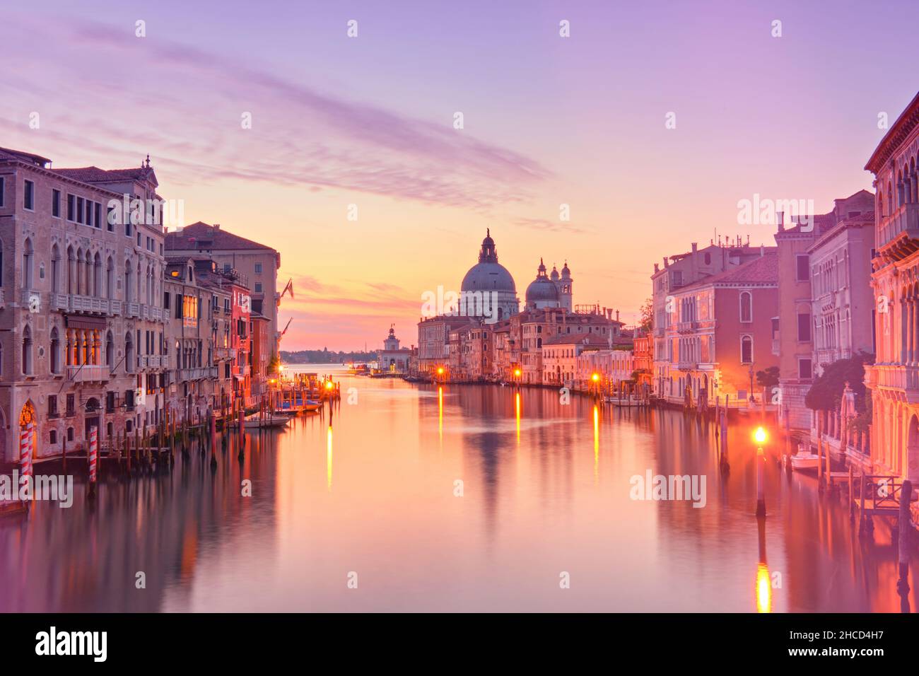 Romantic Venice at dawn, sunrise. Cityscape image of Grand Canal in Venice, with Santa Maria della Salute Basilica reflected in calm sea. Stock Photo