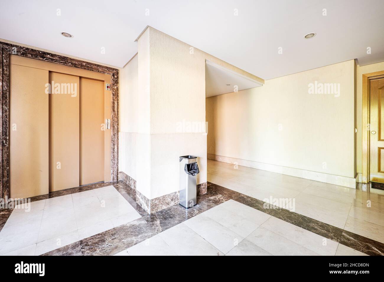Lobby of apartment building with marble floors and cream-colored elevator Stock Photo