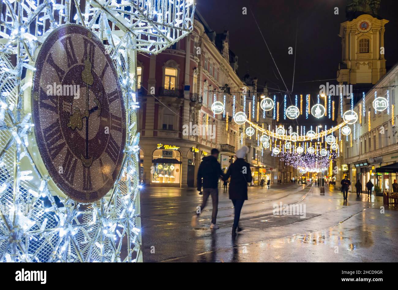 Graz, Austria-December 02, 2021: Beautiful Christmas decorations with famous Clock Tower on Herrengasse street, at night, in the city center of Graz, Stock Photo
