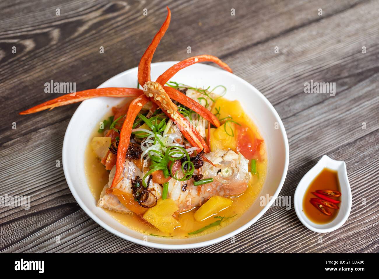 Steamed red snapper fish with ingredients including fish, pineapple, tomato, chili and spices Stock Photo