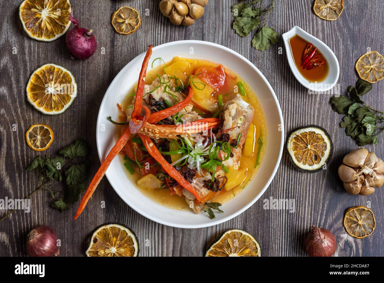 Steamed red snapper fish with ingredients including fish, pineapple, tomato, chili and spices Stock Photo