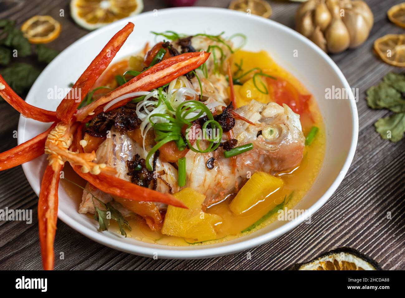 Steamed red snapper fish with ingredients including fish, pineapple, tomato, chili and spices Stock Photo