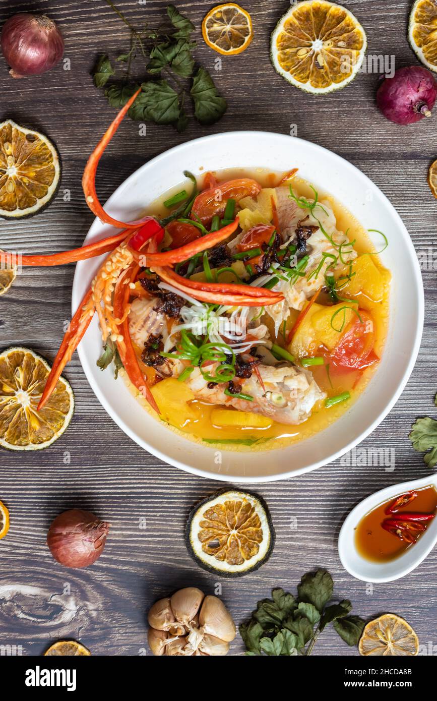 Steamed red snapper fish with ingredients including fish, pineapple, tomato, chili and spices Stock Photo