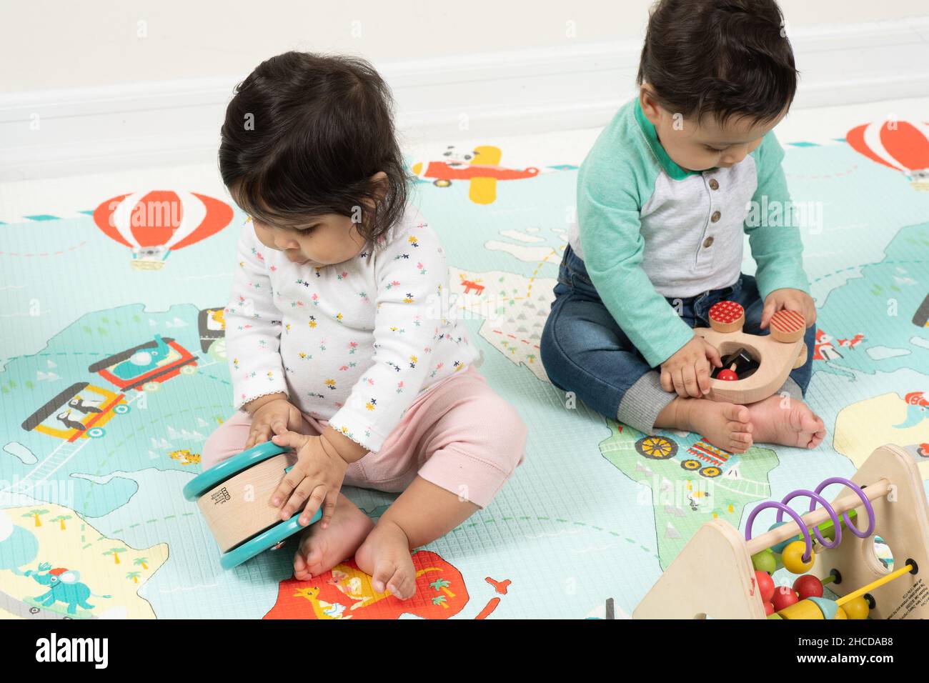 8 month old fraternal twin babies, a boy and a girl sitting near each other playing separately Stock Photo