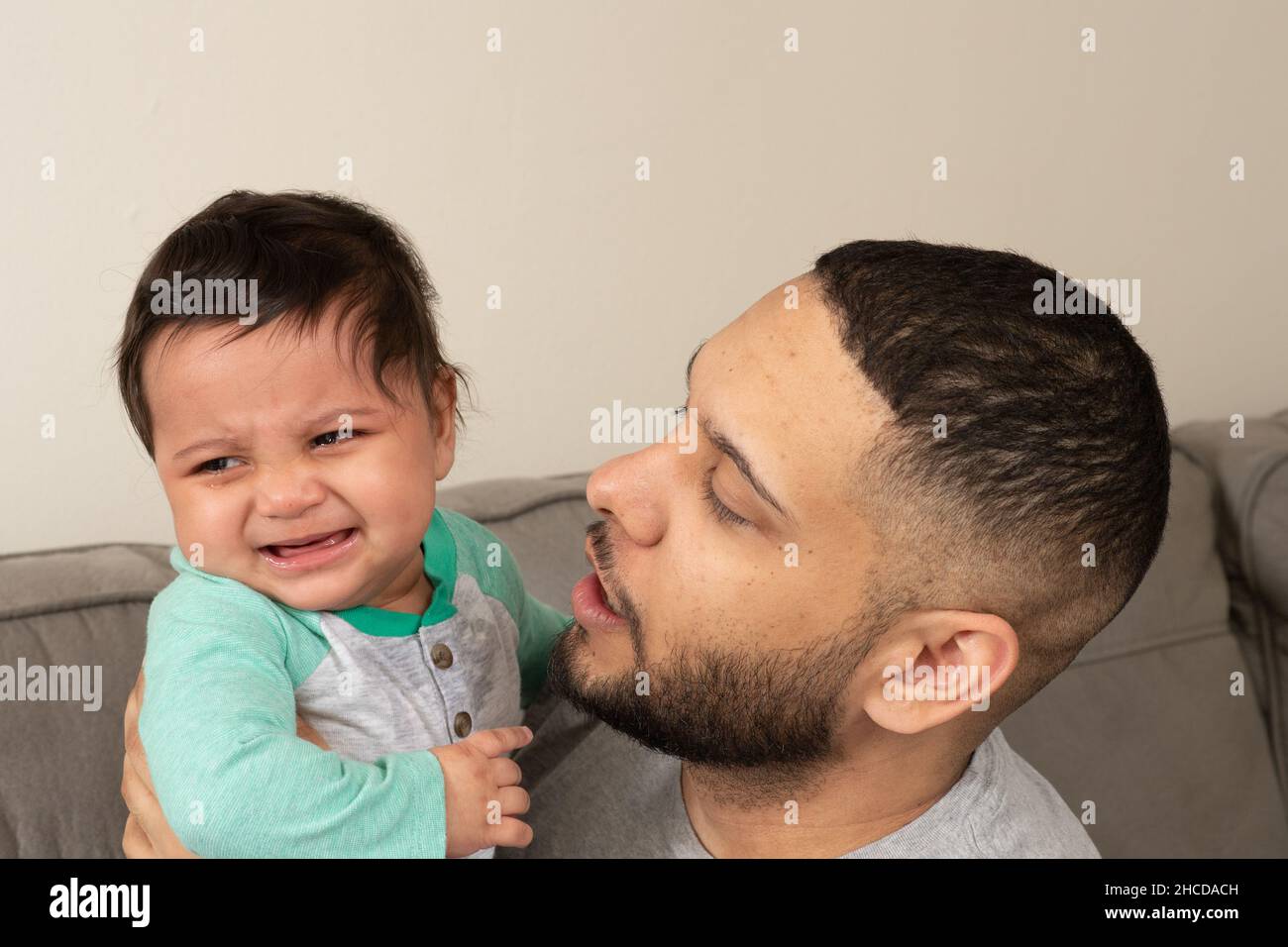 8 month old baby boy, crying, held by father who is trying to comfort him Stock Photo