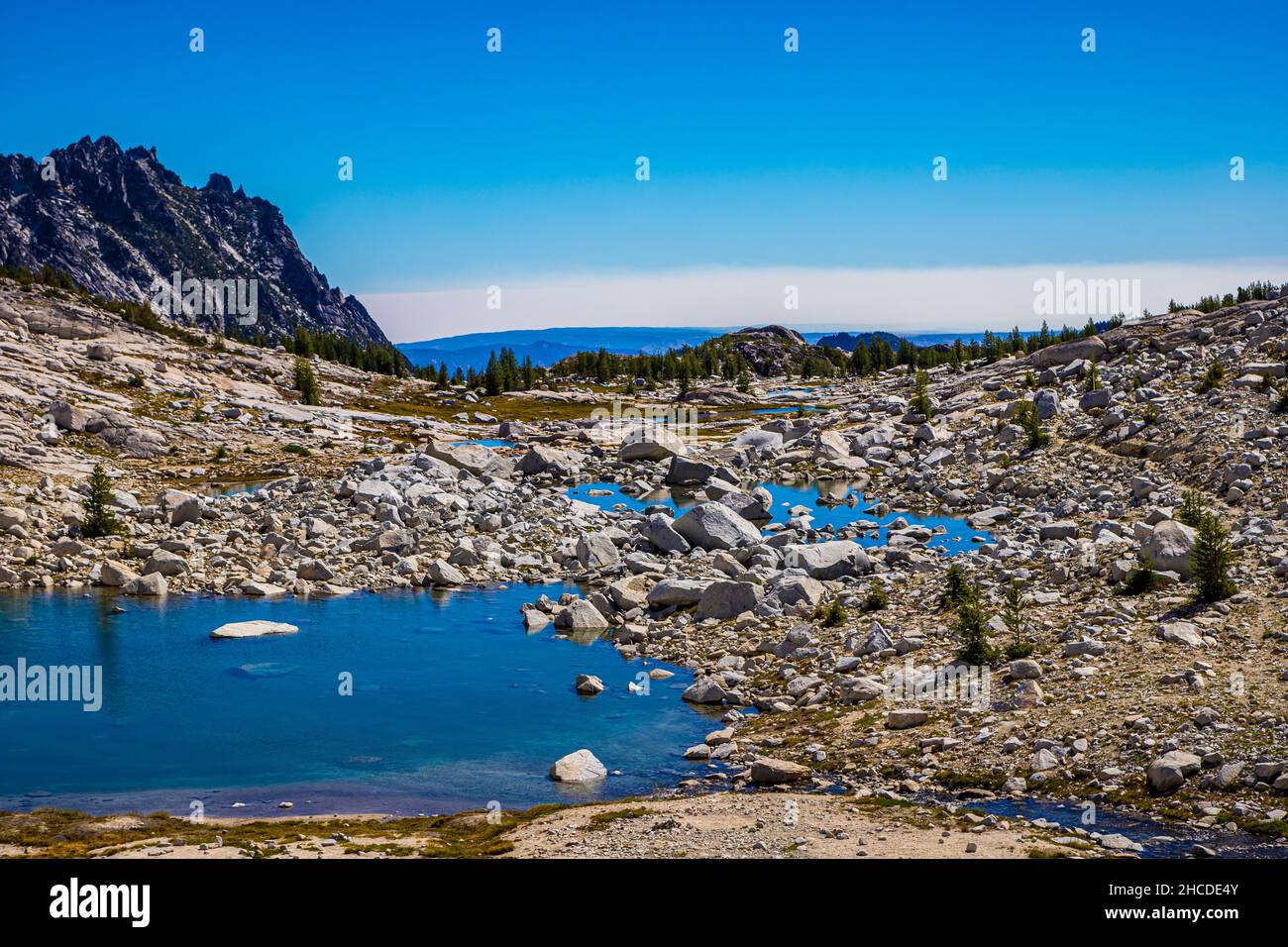 Looking out over rocky stone ponds reflecting the sky in The Enchantments of Alpine Lakes Wilderness in the Cascades, Washington, USA Stock Photo