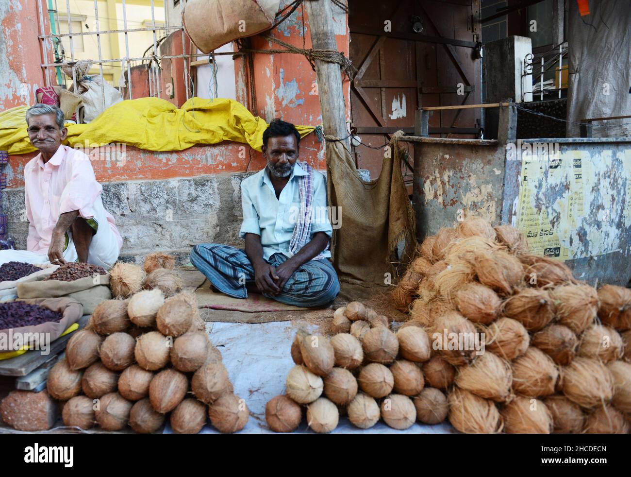 A coconut vendor selling his dried coconuts on the main street of Kuppam, Andhra Pradesh, India. Stock Photo