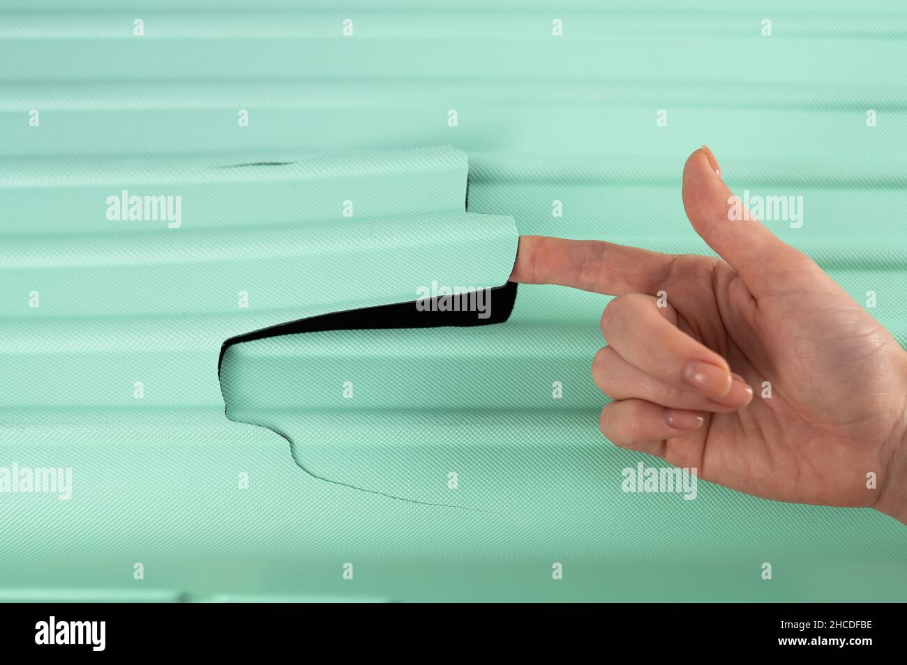 A woman demonstrates a broken suitcase on a white background. Damaged