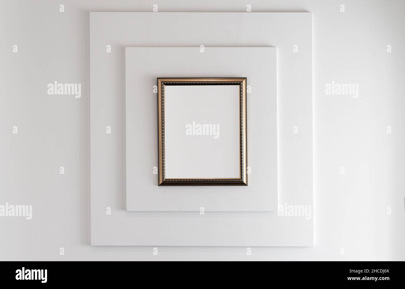 Wooden frame with blank white copy space area is on a wall with square relief decoration pattern. Front view, background photo Stock Photo