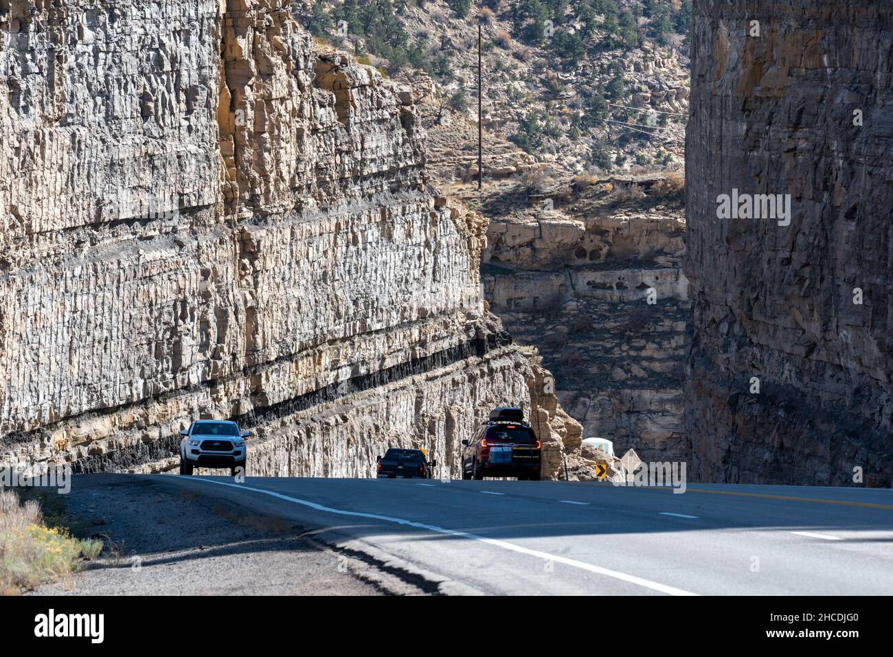 Vehicles driving through a road cut with coal seams on Highway 6 in Carbon County, Utah. Stock Photo