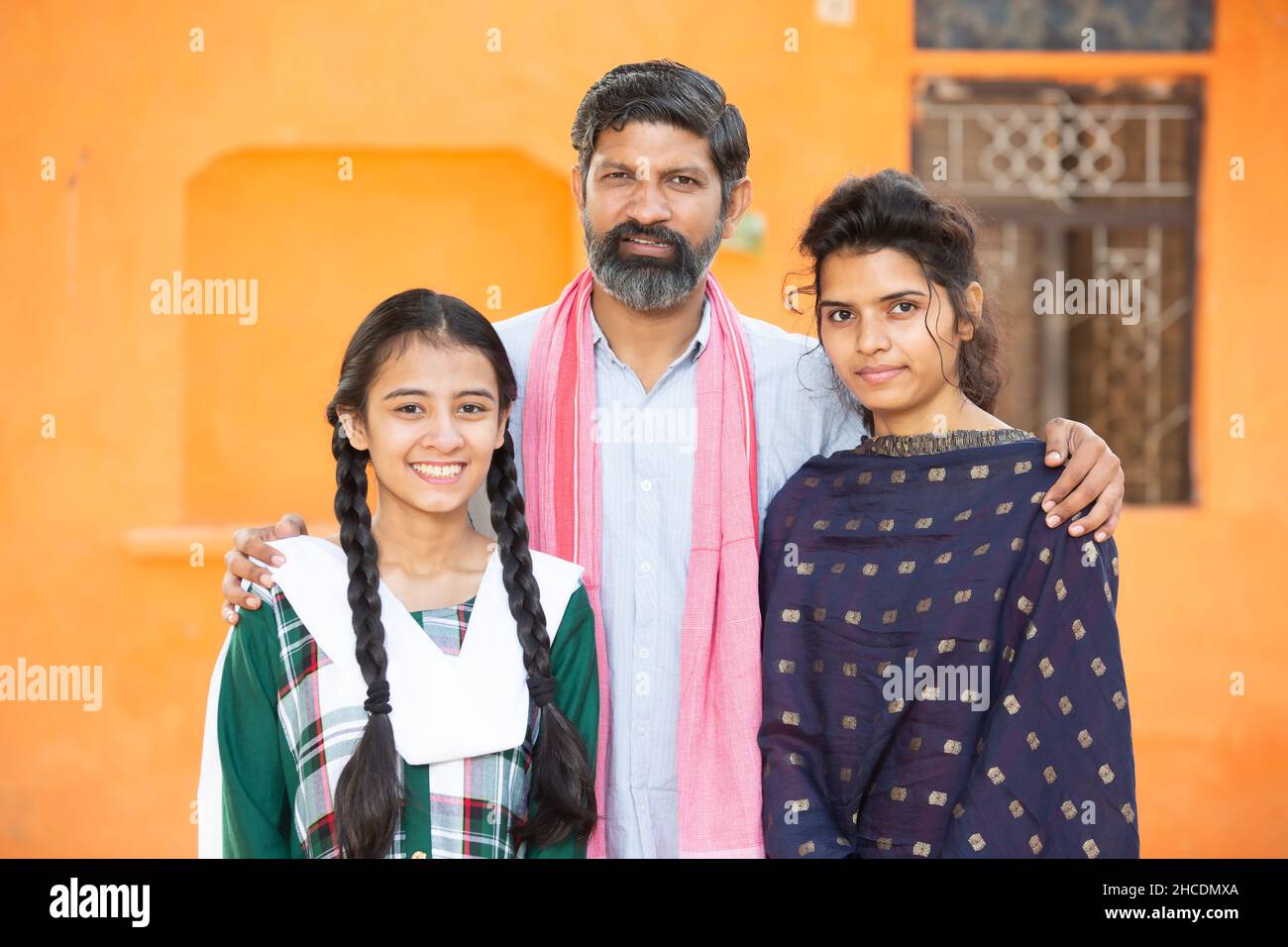 Portrait of happy traditional Indian father with his two young beautiful daughters showing his love and support, small family, rural india. beard Man Stock Photo