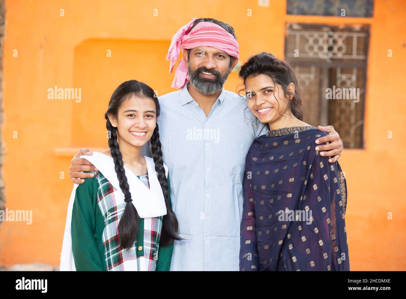 Portrait of happy traditional Indian father with his two young beautiful daughters showing his love and support, small family, rural india. beard Man Stock Photo