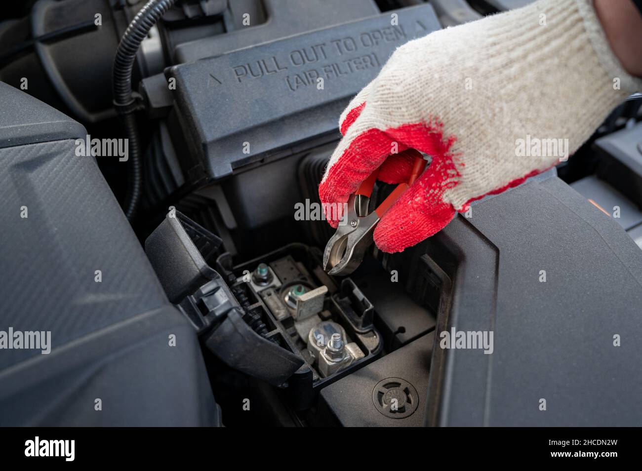 Driver's hand checking the condition of the car's battery. Stock Photo