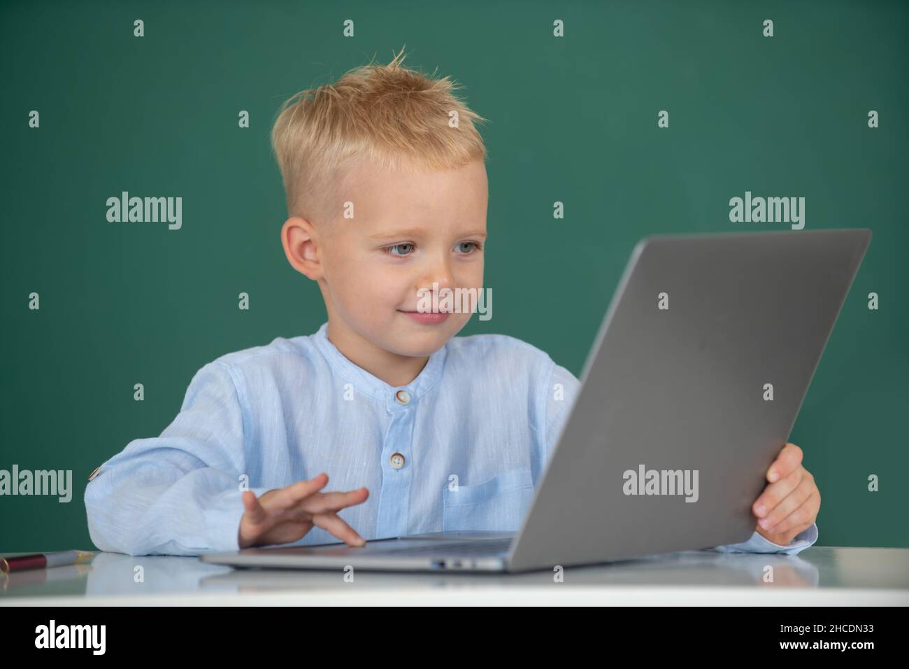 School boy learn lesson sitting at desk, studying online e-learning use internet. Genius child programming, computer training. Stock Photo