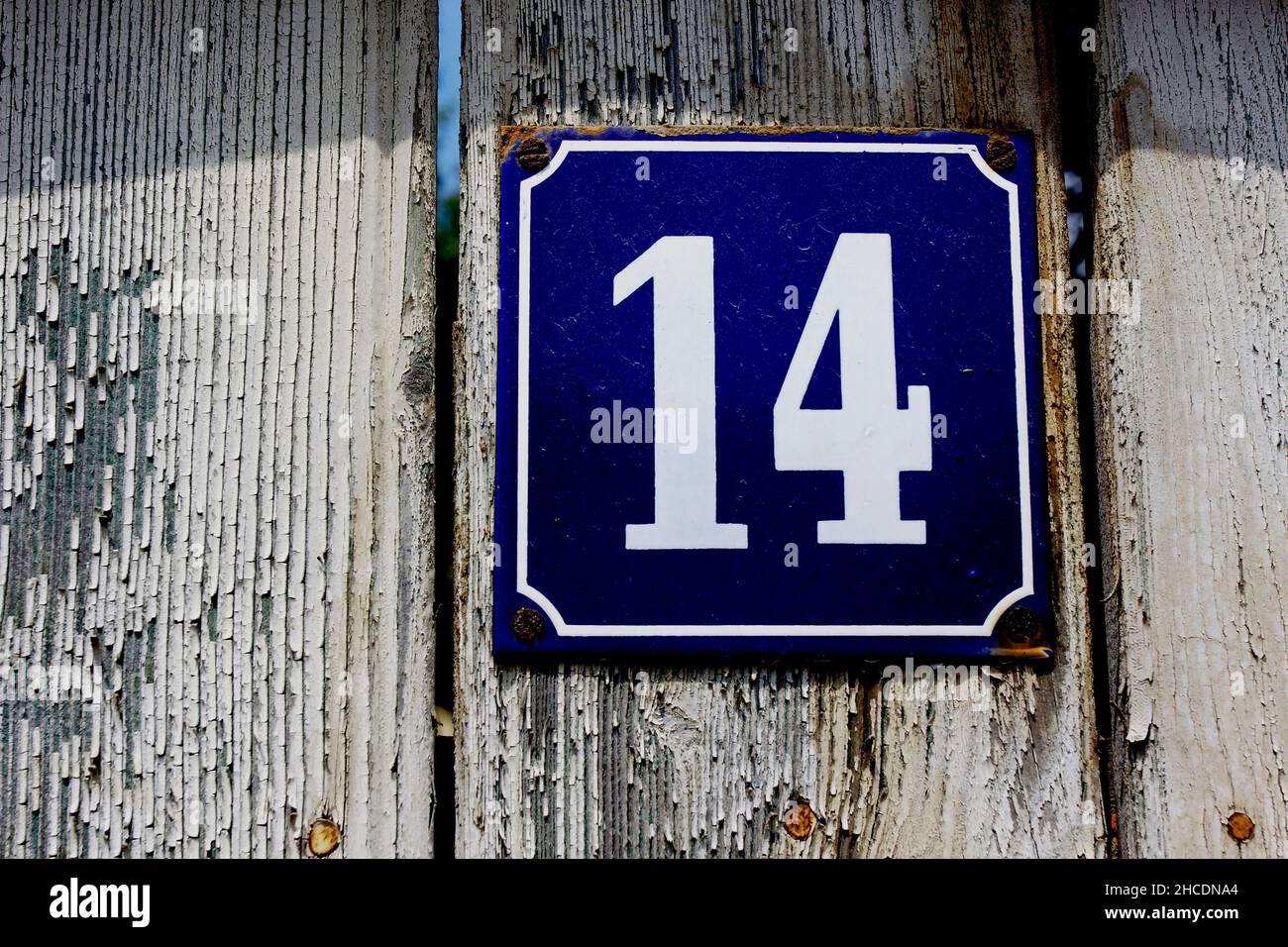 Number 14 on an enamel sign attached to a garden fence Stock Photo