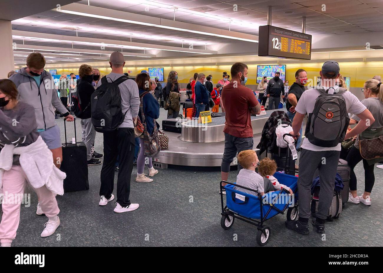 Travelers are seen waiting for their luggage at a baggage carousel at Orlando International Airport two days after Christmas. Due to flight crew shortages as a result of the COIVD-19 Omicron variant and due to other reasons, 760 flights to, from or within the US were canceled, and another 930 were delayed on December 27, 2021. Due to flight crew shortages as a result of the COIVD-19 Omicron variant and due to other reasons, 760 flights to, from or within the US were canceled and another 930 were delayed on December 27, 2021. Stock Photo