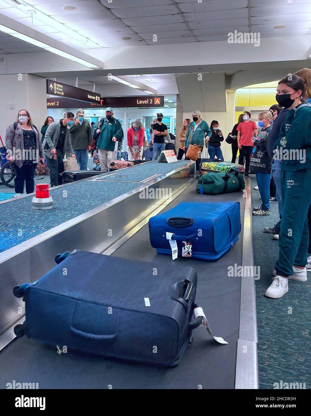 Travelers are seen waiting for their luggage at a baggage carousel at Orlando International Airport two days after Christmas. Due to flight crew shortages as a result of the COIVD-19 Omicron variant and due to other reasons, 760 flights to, from or within the US were canceled, and another 930 were delayed on December 27, 2021. Due to flight crew shortages as a result of the COIVD-19 Omicron variant and due to other reasons, 760 flights to, from or within the US were canceled and another 930 were delayed on December 27, 2021. Stock Photo