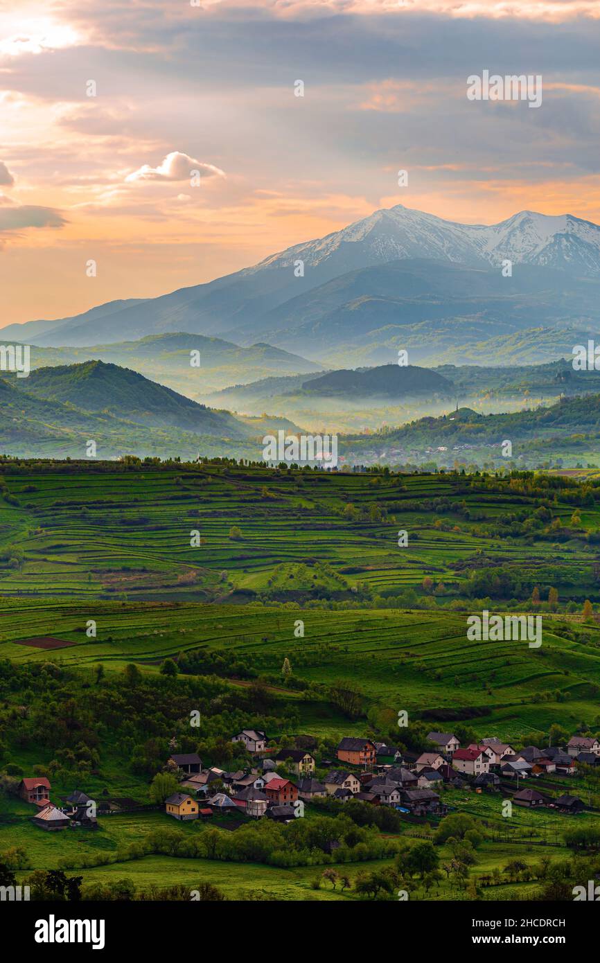 Maramures county with houses from Ieud town and the mighty Carpathian Mountains behind, during a misty sunrise. Photo taken on 16th of May 2021 near I Stock Photo