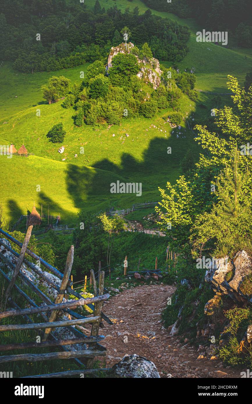 Summer view of the Wolf Rock looking down on a small remote mountain village on Fundatura Ponorului. Photo taken on 12th of June 2021 in Fundatura Pon Stock Photo