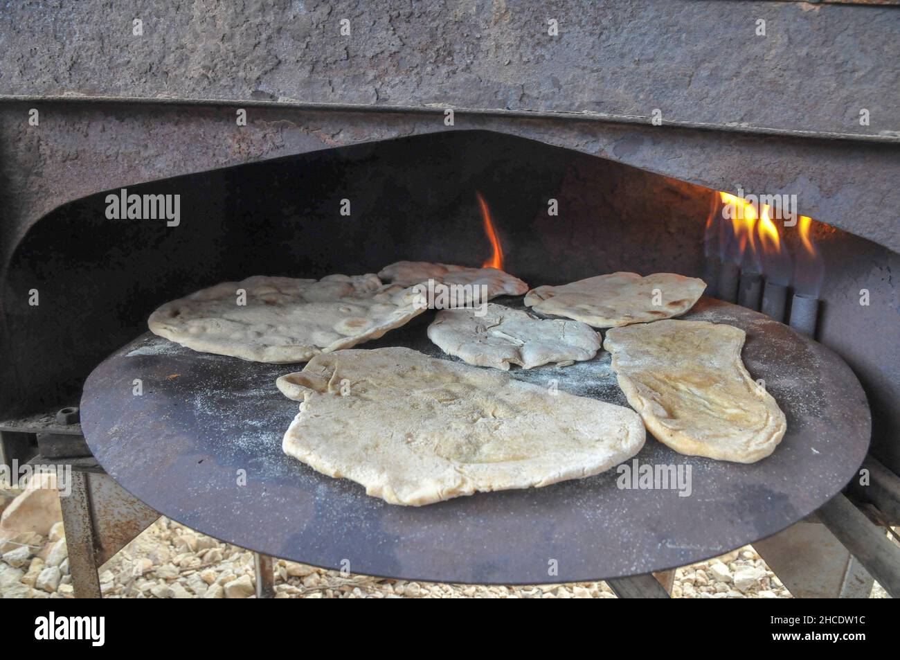 Outdoor Cooking preparing a flat bread Pita on a Saj - an iron dome shaped pan that is used to cook the pita bread on. It is placed over a source of h Stock Photo